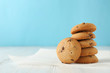 Delicious oatmeal cookies with chocolate chips on wooden table against color background