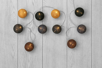 Wall Mural - Glowing Christmas lights on wooden background, top view