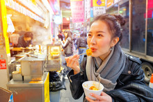 Asian Young Woman Eating Chinese Steamed Dumpling On A Street In Hong Kong