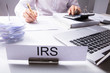 IRS Nameplate In Front Of Accountant Calculating Tax