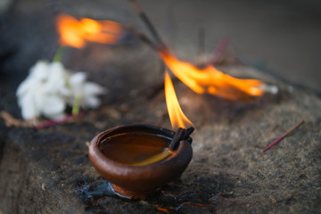 Wall Mural - Burning clay oil lamp with white flowers a buddhist and hindu temple