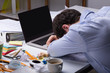 © Andrey Popov - Exhausted Businessman Resting On Messy Desk With Open Laptop