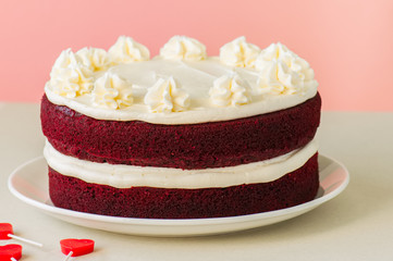 Red velvet cake with cream cheese frosting on a white plate