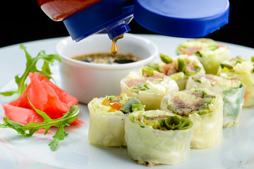 Wall Mural - Process of preparing fresh Vegetable Spring Rolls with soy sauce and ginger in a white plate