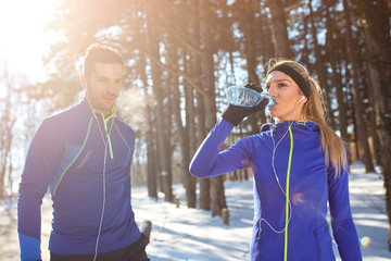 Woman drinking water in woods on training.