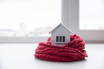 Wall Mural - house in winter - heating system concept and cold snowy weather with model of a house wearing a knitted cap