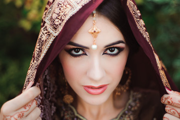 Portrait of beautiful indian girl . Young hindu woman model with tatoo mehndi and kundan jewelry.