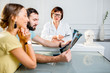 © rh2010 - Young couple having a consultation with senior doctor discussing x-ray print sitting in the white office