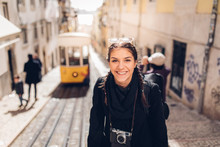 Young Cheerful Woman Walking Down The Street Of Lisbon.Amazed Tourist Visiting Europe Off Season During Winter.Student In Portugal,Europe On A Spring Brake Trip Exploring Big Cities.Positive Female