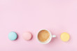 Cozy morning breakfast. Cup of coffee and colorful macaron on pastel pink background top view. Fashion flat lay style. Sweet macaroons.