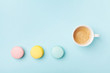 Coffee and colorful macaron on pastel blue background top view. Cozy morning breakfast. Fashion flat lay style. Sweet macaroons.