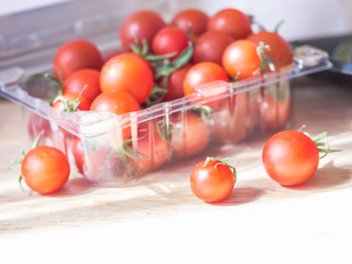 Wall Mural - Vivid red tomatoes in plastic box on the table in the kitchen. Dieting or healthy concepts.