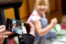 A Cheerful Child Is Photographed On A Smartphone