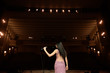 © nagaets - Beautiful singer against the auditorium. Back view girl in long gown performing on stage.