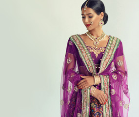 Portrait of beautiful indian girl. Young hindu woman model with kundan jewelry set. Traditional India costume lehenga choli or sari
