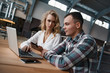 © stacestock - Two colleagues are looking for something in the smartphone. They are working on the laptop. The woman tells something to the man.