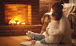 canvas print picture - family mother and child hugs and warm on winter evening by fireplace.