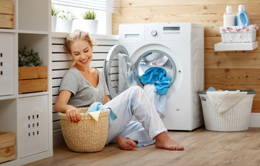 Wall Mural - Happy housewife woman in laundry room with washing machine  .