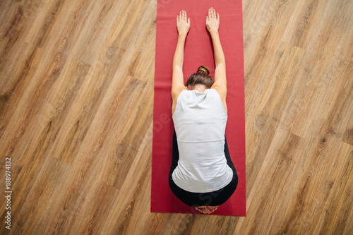Poster Woman doing the Child's pose on red yoga mat. Balasana