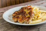 Fototapeta Tęcza - Chicken thigh with French fries on a wooden background. chicken thigh on a plate. rustic food