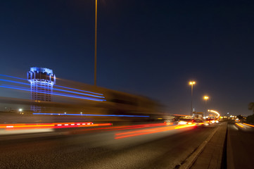 Jeddah water tower at night, with car lights motion on the street.