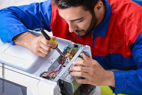 Fotografía Young repairman fixing and repairing microwave oven