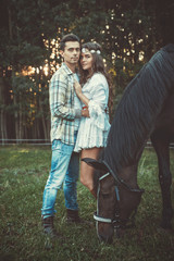 Wall Mural - Young couple in embrace on the meadow with a horses