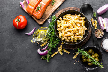 Poster - Pasta, salmon fish and ingredients for cooking on black background, top view. Italian food