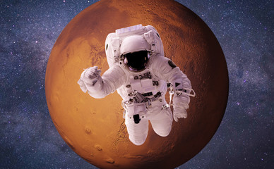 Wall Mural - astronaut performing a space walk around the red planet mars