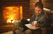 © JenkoAtaman - young woman   reading a book by the fireplace on a winter evening.