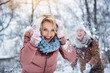 © Yakobchuk Olena - Waist up portrait of excited young woman covering her head from snow by hands. She is looking at camera and smiling. Man is throwing snowball on her on background