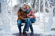 © Yakobchuk Olena - Full length portrait of cute loving couple sitting on bench and hugging. They are looking at camera and smiling. Winter romance concept
