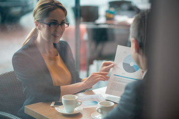 Wall Mural - Portrait of cheerful businesswoman demonstrating information to colleague while situating at desk. Profession concept