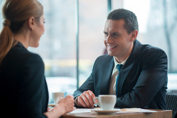 Aufkleber - Outgoing man telling with cheerful female comrade while tasting mug of beverage. Business meeting concept
