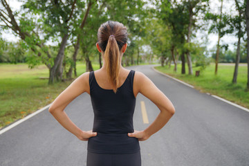 Wall Mural - Back view of young fitness woman running on the road in the morning, People and sport concept, Selective focus