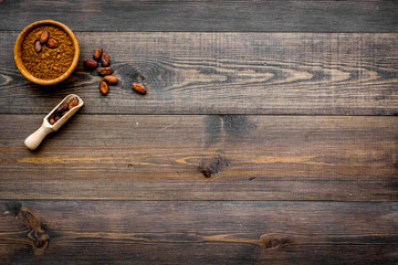 Main ingredient for chocolate. Cocoa powder in bowl near cocoa beans on dark wooden background top view copy space