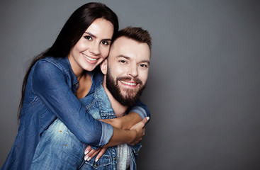 Beautiful and happy young couple in love in casual clothes, the guy is holding the girl on his back.