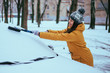 young woman clean car after snow storm