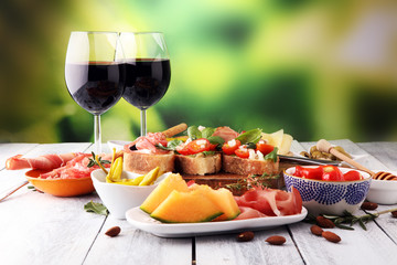 Italian antipasti wine snacks set. Cheese variety, Mediterranean olives, pickles, Prosciutto di Parma, tomatoes, artichokes and wine in glasses