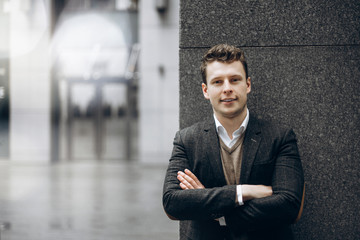 Portrait of a handsome smiling man in a stylish jacket on a gray background outdoors