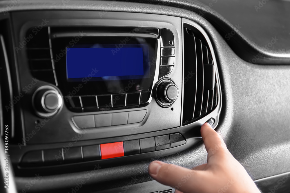 Man switching on air conditioner in car