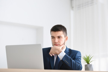 Poster - Young man in suit using laptop at workplace