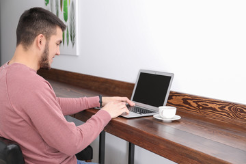 Poster - Young man using modern laptop in cafe