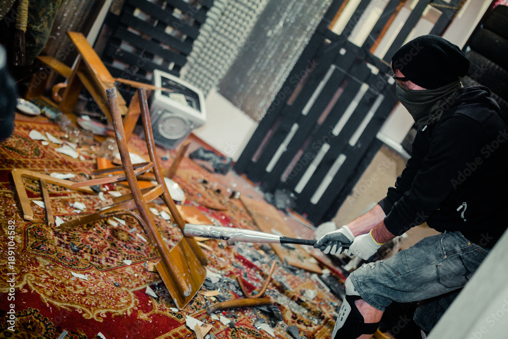 man in the rage room smashing chair and old computer with a baseball bat - obrazy, fototapety, plakaty 