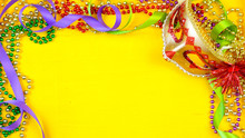 Mardi Gras Overhead Background With Colorful Masks And Beads On Rustic Yellow Wood Background, With Copy Space.