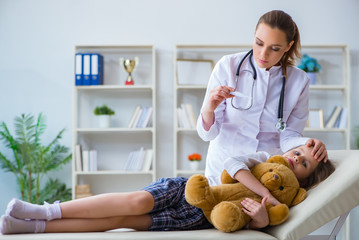 woman female doctor examining little cute girl with toy bear