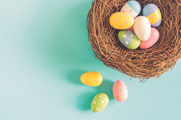 Colorful easter eggs in nest on pastel color background with space.