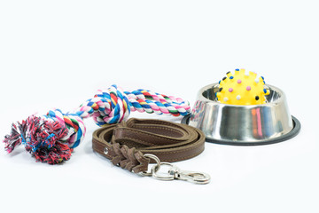 Pet supplies set about stainless bowl, rope, rubber toys and leather of leash for dog or cat on white background