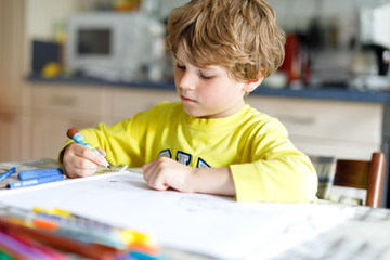 Wall Mural - Tired kid boy at home making homework writing letters with colorful pens