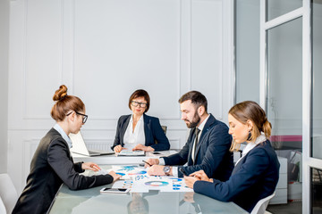 Business people working with charts and documents sitting at the table during the conference in the office